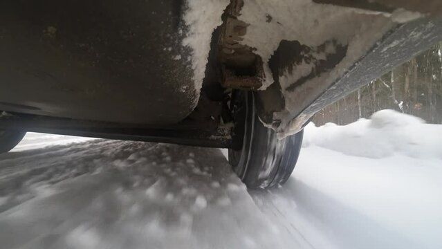 View from bottom of car on suspension and wheels. Car accelerates on winter highway. Bottom of car. Gopro kind of car bottom. Wheels rotating under car. Suspension and shock absorber displacement.
