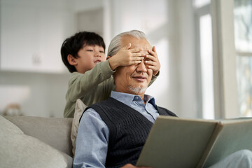elderly asian grandfather having a good time with grandson at home