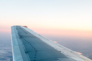 Fototapeta na wymiar pink sunset from above, over winter terrain and airplane wing