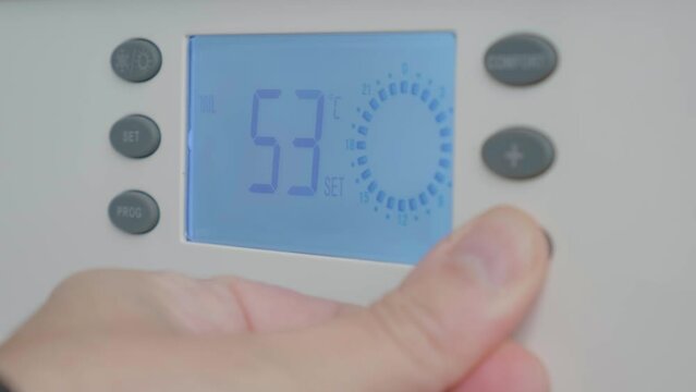Hand reduce temperature on gas boiler control panel for comfort home heating and energy efficient. Concept of energy saving and heat conservation