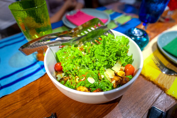 Bowl of green leafy vegetable sprinkled with nuts and cherry tomato