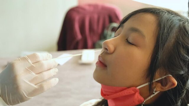 Doctor testing the COVID-19 RAPID SARS-COV2 Antigen Test Kit (ATK) Nasal Swap on an Asian girl.
