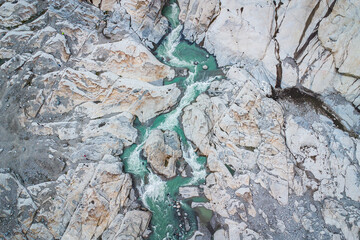 Wild river with green glacial water from melting ice streaming down between rocks