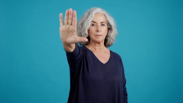 Serious mature woman gesturing with her hand prohibition