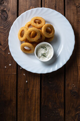 Onion rings in breadcrumbs on a white plate
