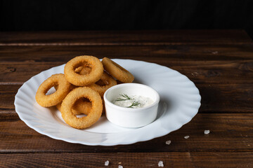 Onion rings in breadcrumbs on a white plate