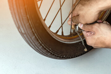 Hands of man check inflator pressure and inflates tire on motorcycle with bicycle floor pump. Man...