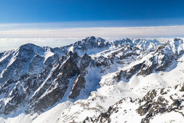 Fototapeta na wymiar Snowy winter high mountain landscape. A panoramic view from the top of The Lomnicky peak in High Tatras National Park, Slovakia, Europe.