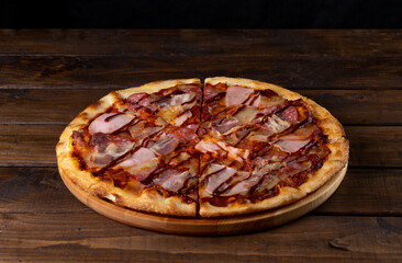 Pizza on a plate on a wooden background, cut into pieces