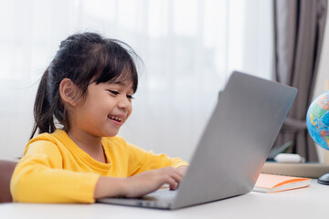 First day at school. Asian little girl using a laptop computer, studying through online e-learning...