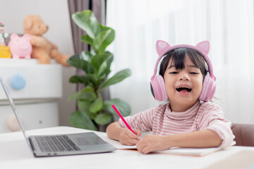 Asian little girl in headphones have video call distant class with teacher using laptop, study online on computer, homeschooling concept