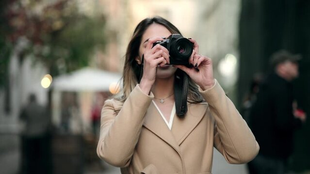 Charming Woman with camera on the street. Creative professional female photographer making urban photo session. Outdoor smiling lifestyle portrait of pretty girl