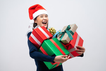 Portrait of Attractive Asian woman in Christmas hat holding stack of gift boxes isolated grey background