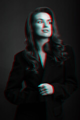 Pop-art concept. Portrait of beautiful woman with dark suit and big wavy hair in red and blue color split effect. Model standing in grace pose and looking aside camera. Futuristic looking style
