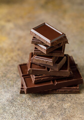 Broken chocolate pieces on dark background. Stack of dark chocolate. Chocolate concept