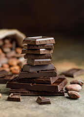 Broken chocolate pieces on dark background. Stack of dark chocolate. Chocolate concept