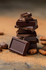 Broken chocolate pieces on dark background. Stack of dark chocolate. Chocolate concept