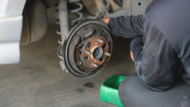 Auto mechanic removing bolts to replace car rear brake bearings