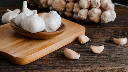 organic Raw garlic bulb, garlic cloves on wooden cup, wooden cutting board, wooden table and garlic cloves of food ingredients