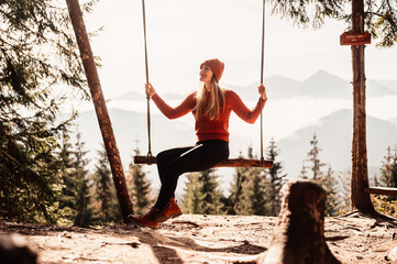 Woman swinging on swing in sunny winter dayin the ferest. Wooden swing with swinging free, happy...