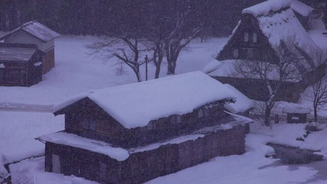 Snow falls on historic Japanese gassho-zukuri houses in mountain village at dawn