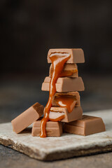 Chocolate with salted caramel on dark background. Stack of milk chocolate. Chocolate concept