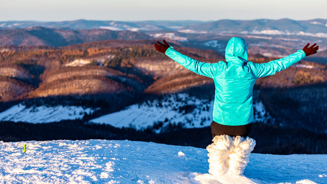 backpacker girl admires panorama of snowy mountains from the summit at sunset, hiking on snowy ridge in Bieszczady mountains, polonina carynska
