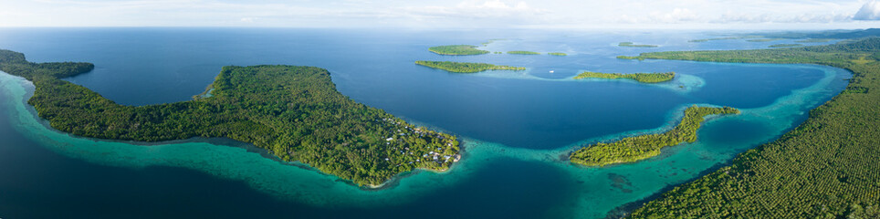 A scenic tropical island is fringed by a coral reef in the Solomon Islands. This beautiful country...