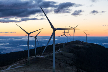 A group of wind power plants early in the morning while sunrise in Austria