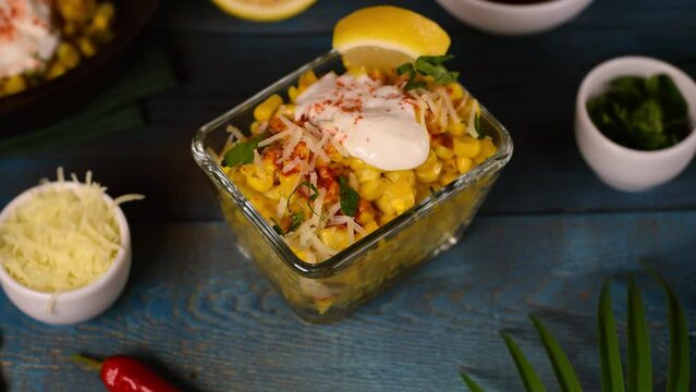 Esquites, grilled corn, served with cheese, sour cream and chili powder in cup and with squeezed lemon juice. Mexican street food meal. Elote corn cup