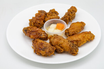 Korean Fried Chicken Wings on a White Plate with a Side of Pickled Radishes