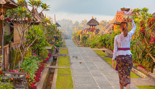 Beautiful balinese girl in traditional costume walking -   Penglipuran is a traditional oldest Bali village at Bangli Regency - Bali, Indonesia