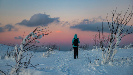 backpacker girl walks along the top of snowy mountains bieszczady at sunset, winter sunset seen from the top of the mountain wielka rawka