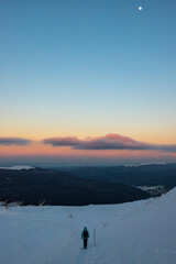 backpacker girl walks along the top of snowy mountains bieszczady at sunset, winter sunset seen from the top of the mountain wielka rawka