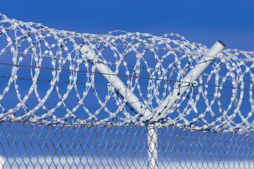 Barb wire roll on a fence with dark blue clouds in the background - obrazy, fototapety, plakaty