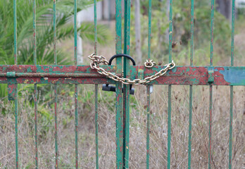 Rusty gate with locked master key and chain.