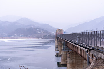 Iron bridge over frozen river in midwinter