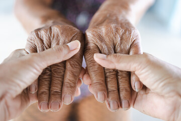 close up young woman holding hand of senior woman, caring for the elderly