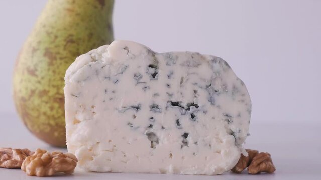 Delicious blue cheese dorblu or gorgonzola with pear and walnuts on white background. Close up. Tasty food. 4k video