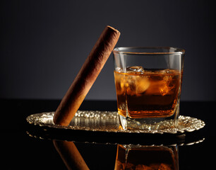 Glass of whiskey with ice and cigar.