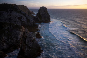 View of the cliffs of Cabo da Roca and the ocean surf at sunset in Sintra, Portugal.