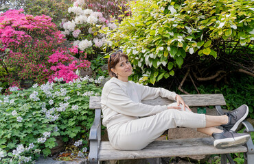 Flowering trees. The girl is sitting on a bench next to flowering trees.