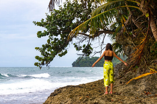 A woman in a long skirt stands on a paradise Costa Rican beach with an island in the background admiring the unique views