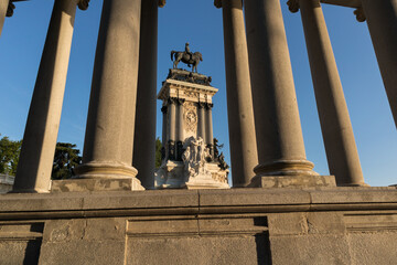 Fototapeta na wymiar Stone column with horse statue in a sunny no clouds in Retiro park, Madrid, Spain