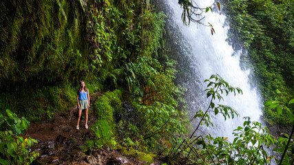A beautiful girl stands near the famous stunning powerful la paz waterfall in an amazing green...