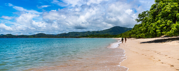 panorama of the famous conchal beach over the pacific in costa rica; paradise beach with turquoise water and green hills in the background