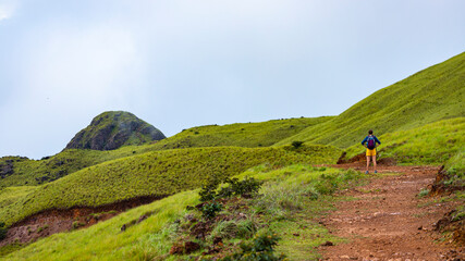 backpacker girl walks along ridge amid cerro pelado mountains during cloudy, misty weather; hiking in green mountains in Costa Rica, Costa Rica rainforests