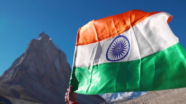 Close up shot of man holding Indian flag in background of Gumbok Rangan mountain at Zanskar, Ladakh, India. Tri color Indian flag fluttering. Republic Day  background