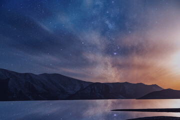 Beautiful night landscape. Small lake and mountains on the bright milky way galaxy with clouds. Starry  night.