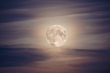 brightly lit full moon among the clouds in the night sky